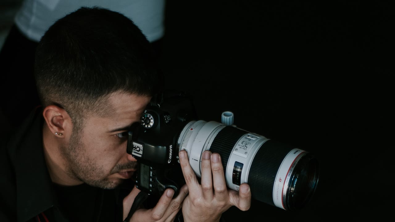 Photographer at work shooting through the viewfinder of a Canon camera with a telephoto lens